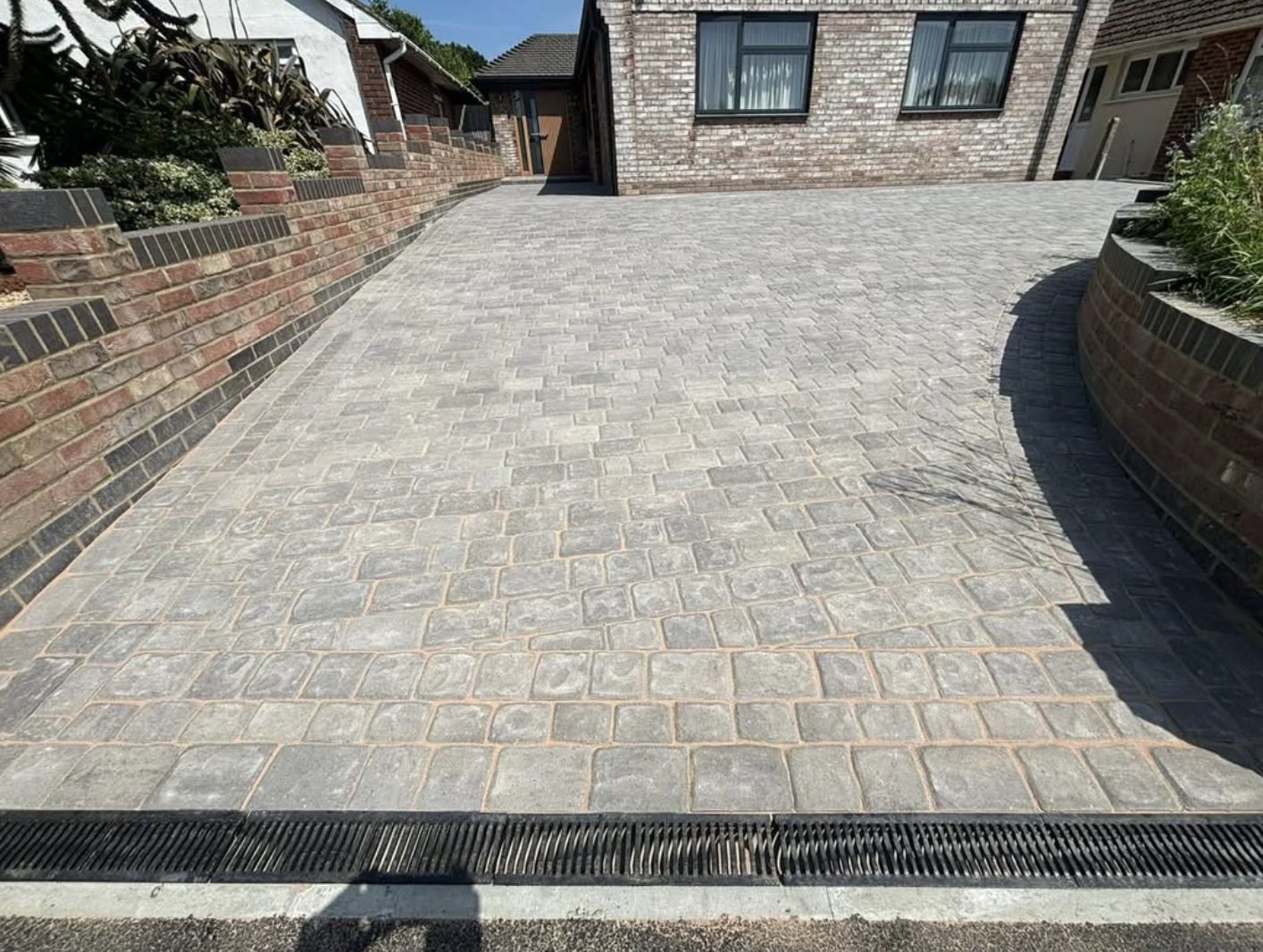 Tumbled grey sett driveway with charcoal border and a threshold channel drain