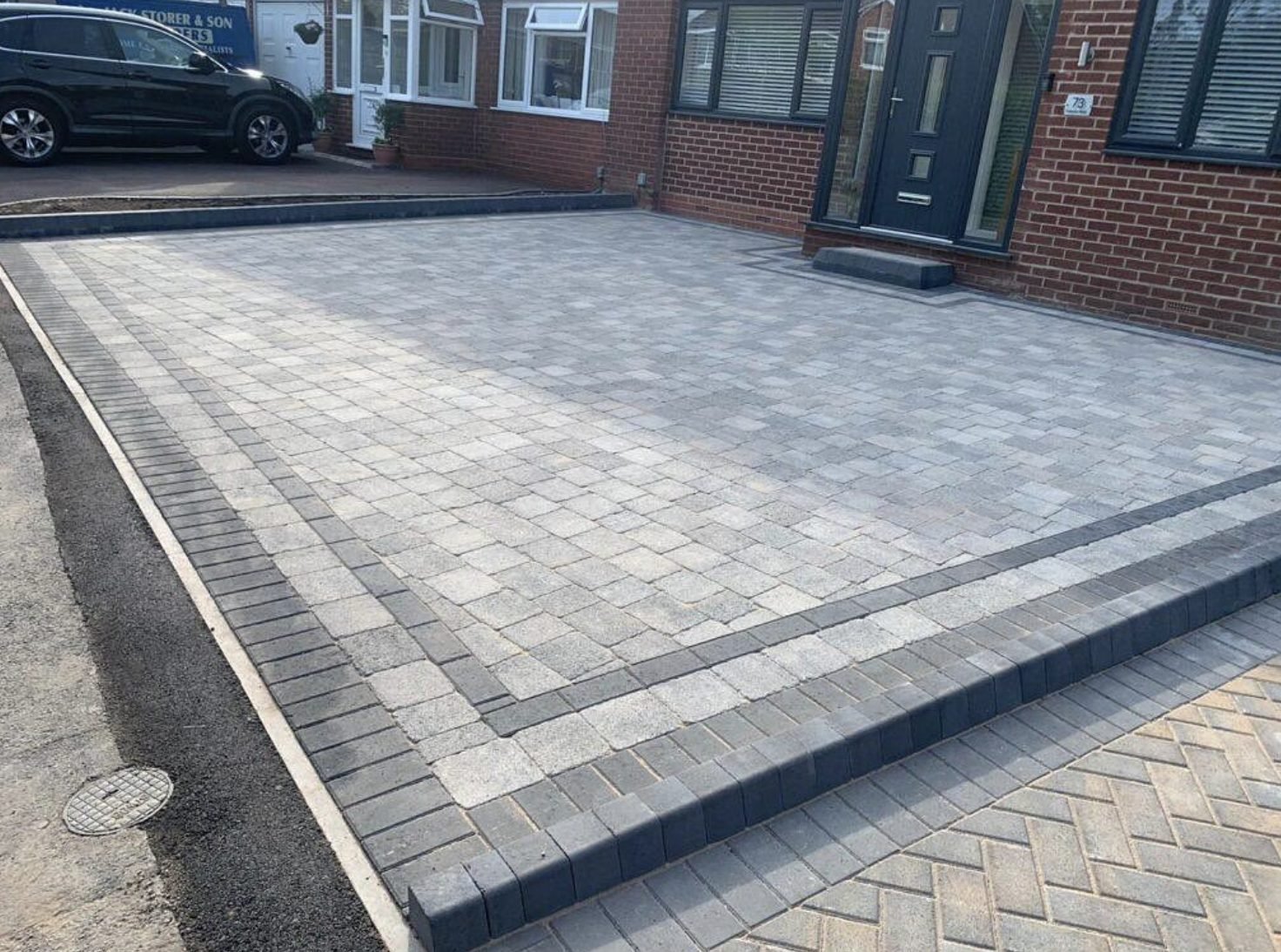 Silver grey block paved driveway with a charcoal double border and kerb edging